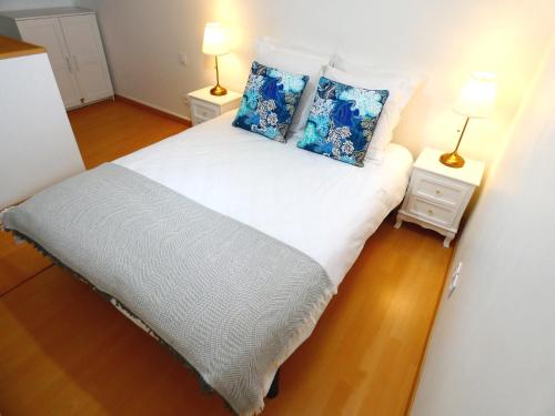 1 dormitorio con 1 cama blanca grande con almohadas azules en Le Pouffre, maison de pêcheur au quartier des artistes, clim, WiFi, en Sète