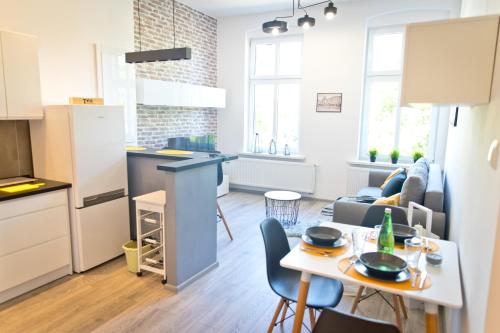 a kitchen and a living room with a table and chairs at Apartament Kalinka in Nysa