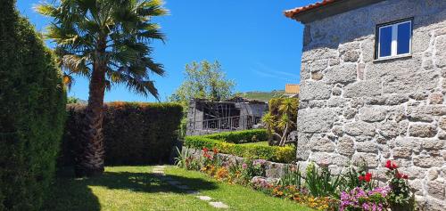 a garden with a palm tree and a stone building at Villas da Quintã in Cabeceiras de Basto