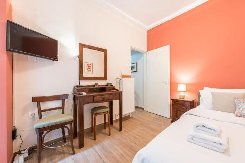 ein Hotelzimmer mit einem Schreibtisch, einem Bett und einem TV in der Unterkunft Cozy studio 5mins walk from Acropolis museum in Athen