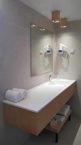 ein Badezimmer mit einem Waschbecken, einem Spiegel und Handtüchern in der Unterkunft Hospedaria Frangaria in Faro