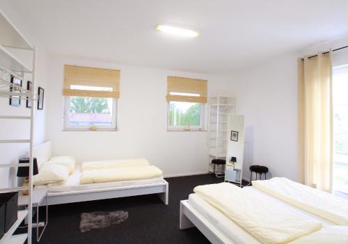 フリードリヒスハーフェンにあるOFFLINE Ferienwohnung Kira in Friedrichshafenの白い壁と窓が備わる客室で、ベッド2台が備わります。