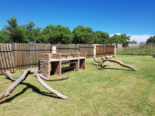 a fire pit in a backyard with logs and a fence at CHEETAH MANOR #4 in Bloemfontein