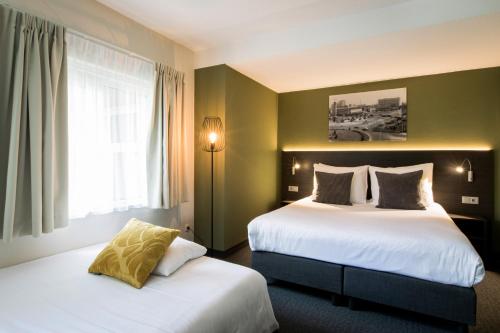 a hotel room with two beds and a window at Hotel Parkzicht Eindhoven in Eindhoven