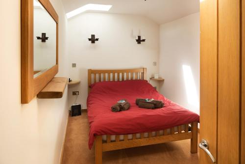 Un dormitorio con una cama roja con dos bolsas. en Owl's Hoot en Thorndon