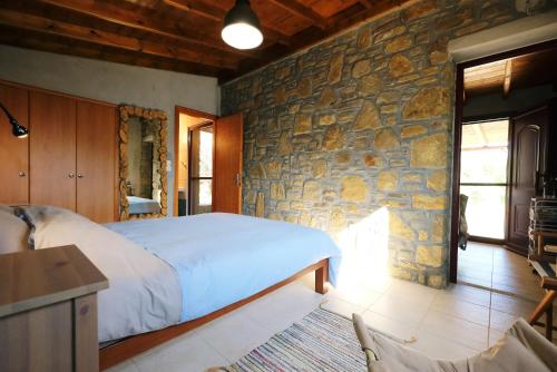 a bedroom with a bed and a stone wall at Limnos Stone House in Kalliópi