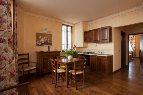 a kitchen with a table, chairs and a refrigerator at Residenza Palazzo Saloni in Montalcino