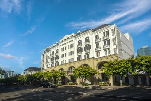 a white building on a city street with a blue sky at Hotel Des Indes Menteng in Jakarta