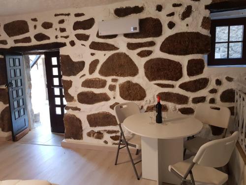 a room with a table and chairs and a stone wall at Casa Bento Teixeira in Belmonte