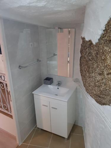 a white bathroom with a sink and a mirror at Casa Bento Teixeira in Belmonte