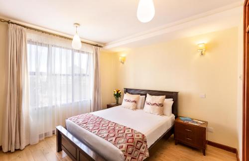 a bedroom with a large bed and a window at Fedha Residences by Trianum in Nairobi