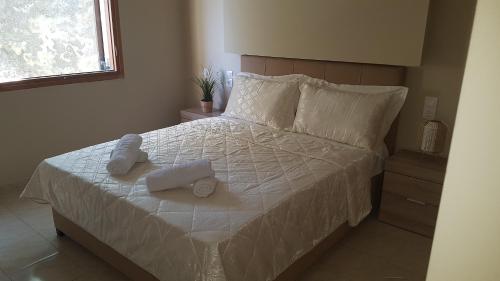 a bedroom with a bed with white sheets and pillows at Chrissomallis Apartments in Skiathos Town