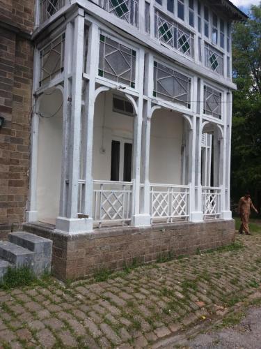 a large white house with a large porch at BRIGHTLANDS HOTEL in Murree