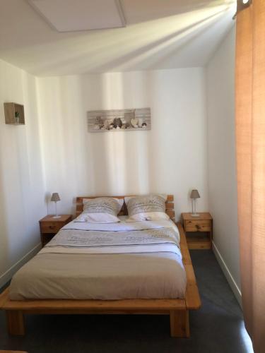 a bedroom with a bed with two nightstands and two lamps at APPT 1.5KM PLAGES DU DÉBARQUEMENT in Tracy-sur-Mer
