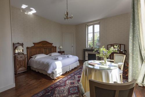 ein Schlafzimmer mit einem großen Bett und einem Tisch mit einem Tisch in der Unterkunft Château des Salles in Saint-Fort-sur-Gironde