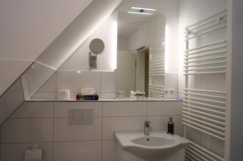 a white bathroom with a sink and a mirror at Ostseehotel Hunhoi in Niesgrau