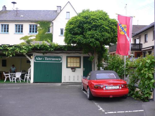 a red car parked in a parking lot in front of a house at Garni-Hotel-Schäfer in Schuld