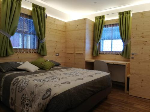a bedroom with a bed with green curtains and a desk at B&B Schlossar Haus in Sappada
