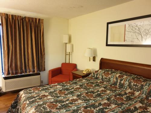 a hotel room with a bed and a chair and a window at Executive Inn Yanceyville in Yanceyville