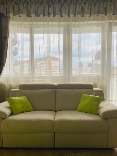 a living room with a couch with two green pillows at Zen Apartment Oradea - FREE Parking in Oradea