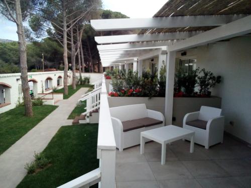 a patio with two white chairs and a table at Club Esse Cala Bitta in Baja Sardinia
