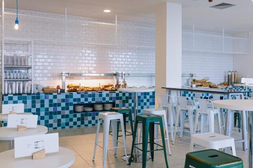 a restaurant with tables and stools in front of a counter at Alua Village Fuerteventura - All Inclusive in Playa Jandia