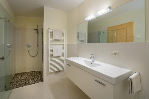 La salle de bains blanche est pourvue d'un lavabo et d'un miroir. dans l'établissement Paalhof, à Castelrotto