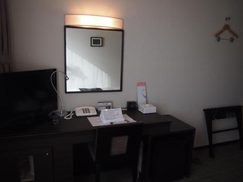 a desk with a mirror and a phone on it at Silk Inn Kagoshima in Kagoshima
