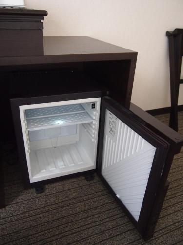 a small refrigerator with its door open next to a desk at Silk Inn Kagoshima in Kagoshima