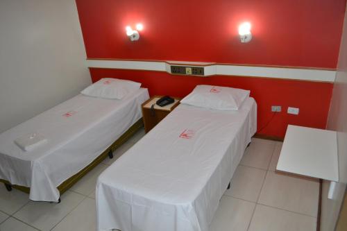 two beds in a room with red walls at Hotel - Pousada do Arco Iris in Osasco