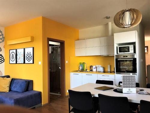 a kitchen with yellow walls and a table and a couch at Apartmány Pinie Lipno in Lipno nad Vltavou