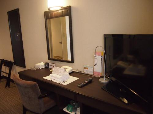 a desk in a hotel room with a television at Silk Inn Kagoshima in Kagoshima