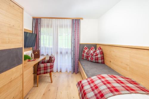 a room with a bed and a desk and a television at Hotel Lindenhof in Ramsau am Dachstein