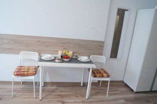 a white table with two chairs and a bowl of fruit on it at Willa Wena in Ustka