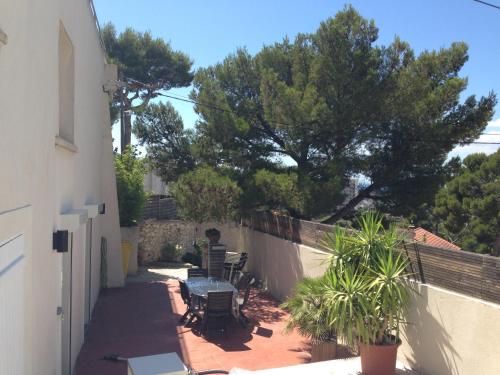 d'une terrasse avec une table, des chaises et un arbre. dans l'établissement Gîte Polema, à Marseille