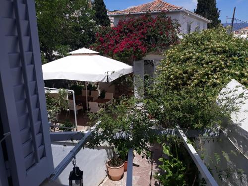 an apartment balcony with flowers and an umbrella at Hotel Miranda in Hydra