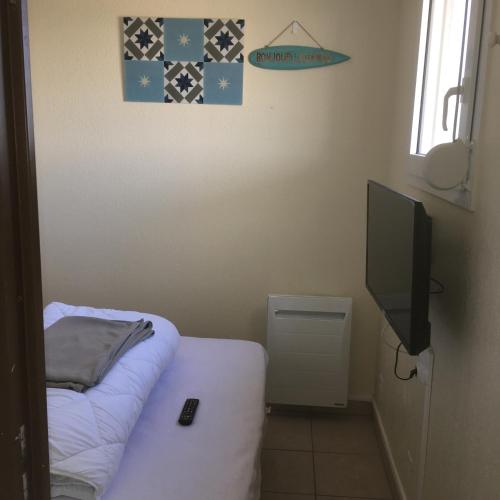 ラカノーにあるBleu marineのベッド1台、薄型テレビが備わる小さな客室です。
