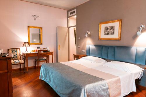 1 dormitorio con 1 cama grande y escritorio en Hotel Terme Salvarola, en Sassuolo