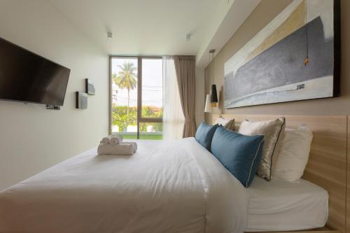Un dormitorio con una gran cama blanca y una ventana en Oceanstone by Holy Cow, 2-BR, 90 m2, pool view, en Bang Tao Beach