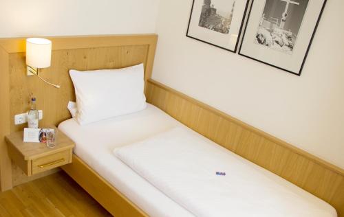 a small room with a bed and a night stand at Hotel Drei König in Immenstadt im Allgäu