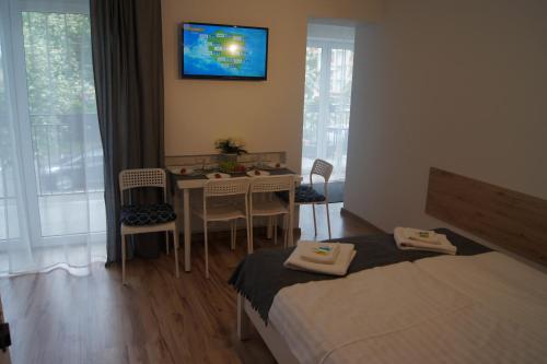 a bedroom with two beds and a table and a television at Willa Wena in Ustka