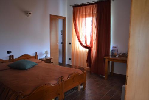 a bedroom with a bed and a window with red curtains at Agriturismo Le oche selvatiche in Lauzacco