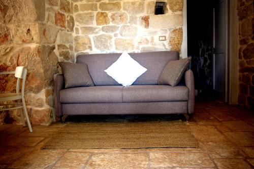 a gray couch with a white pillow sitting in a room at Dimore Storiche - Ulivo di Aldo in Martina Franca