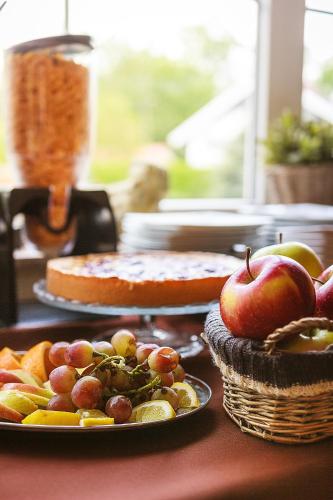 a table topped with plates of grapes and an apple at Willa Kłodzko-Zacisze - sauna, siłownia, komnata solna, parking in Kłodzko