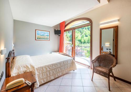a bedroom with a bed and a chair and a window at Locanda Sant' Anna in Argegno