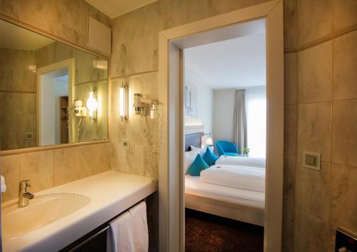 a bathroom with a bed and a sink and a mirror at Hotel Oberland in Triesenberg