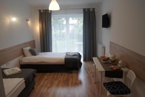 a bedroom with a bed and a table and a window at Willa Wena in Ustka