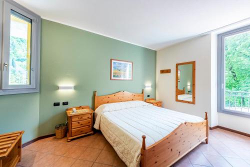 a bedroom with a large bed and two windows at Locanda Sant' Anna in Argegno