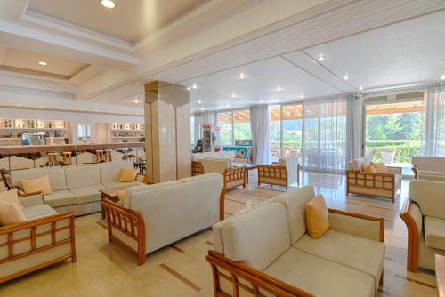 a living room with couches and chairs and a restaurant at Nafsika Hotel - Adults Only in Dassia