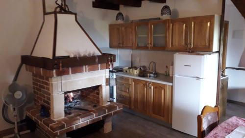 a kitchen with a brick fireplace and a white refrigerator at Weekend House Petar in Lusnić